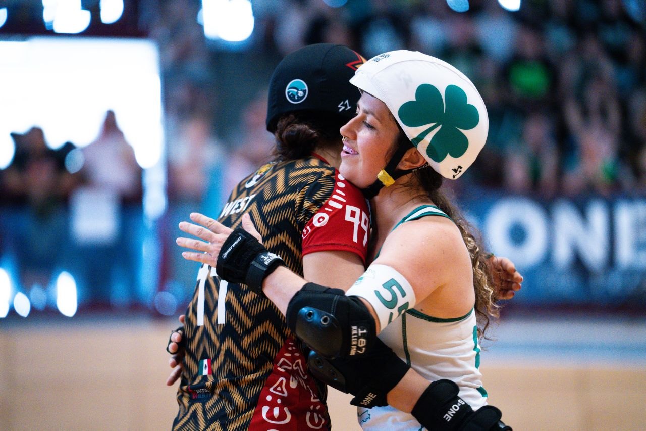 An Ireland skater hugs a Mexico skater on the track after their game.